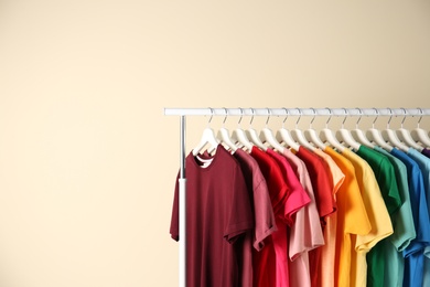 Photo of Many t-shirts hanging in order of rainbow colors on light background