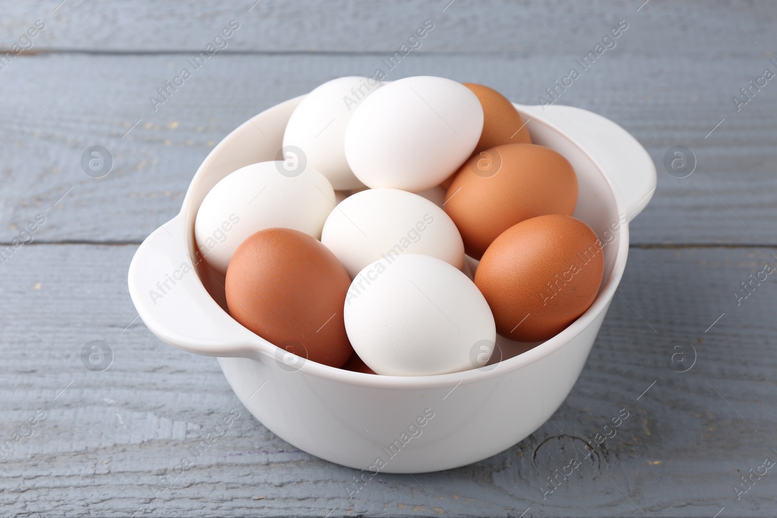 Photo of Unpeeled boiled eggs in saucepan on grey wooden table, closeup