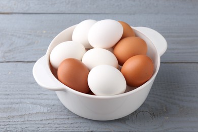 Unpeeled boiled eggs in saucepan on grey wooden table, closeup