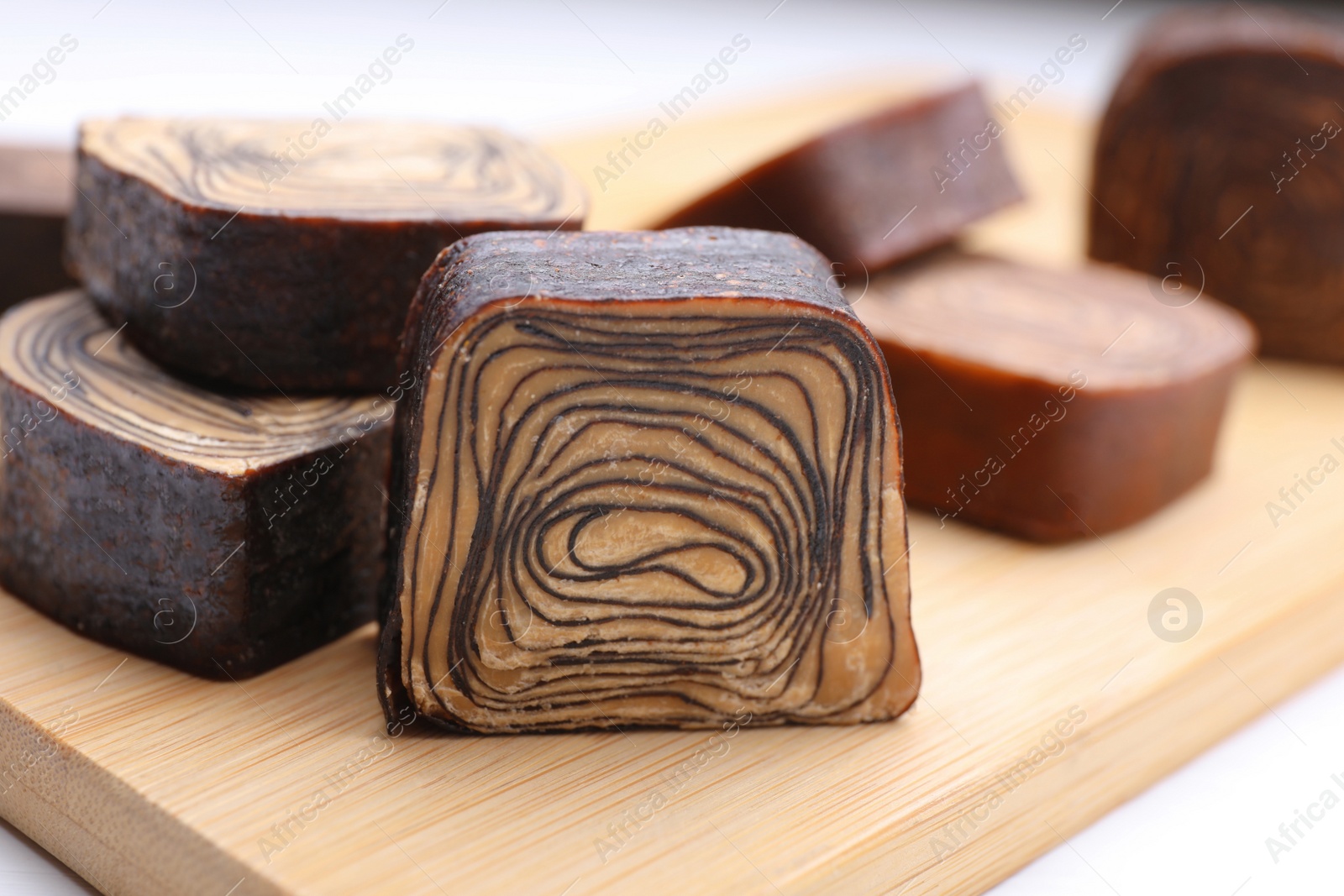 Photo of Tasty chocolate candies on wooden board, closeup