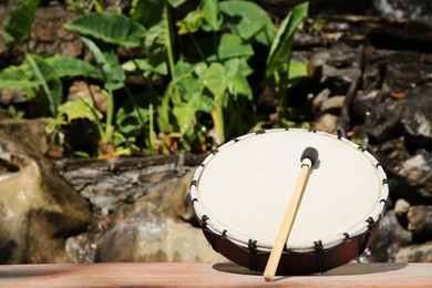 Photo of Drum with mallet outdoors on sunny day, space for text. Percussion musical instrument