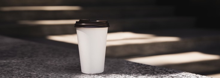 Takeaway cardboard coffee cup with plastic lid outdoors, space for text. Banner design