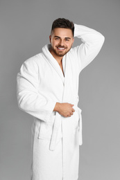 Photo of Happy young man in bathrobe on grey background