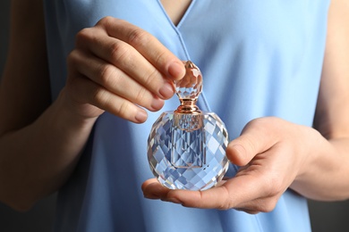 Photo of Woman holding glass perfume bottle, closeup view