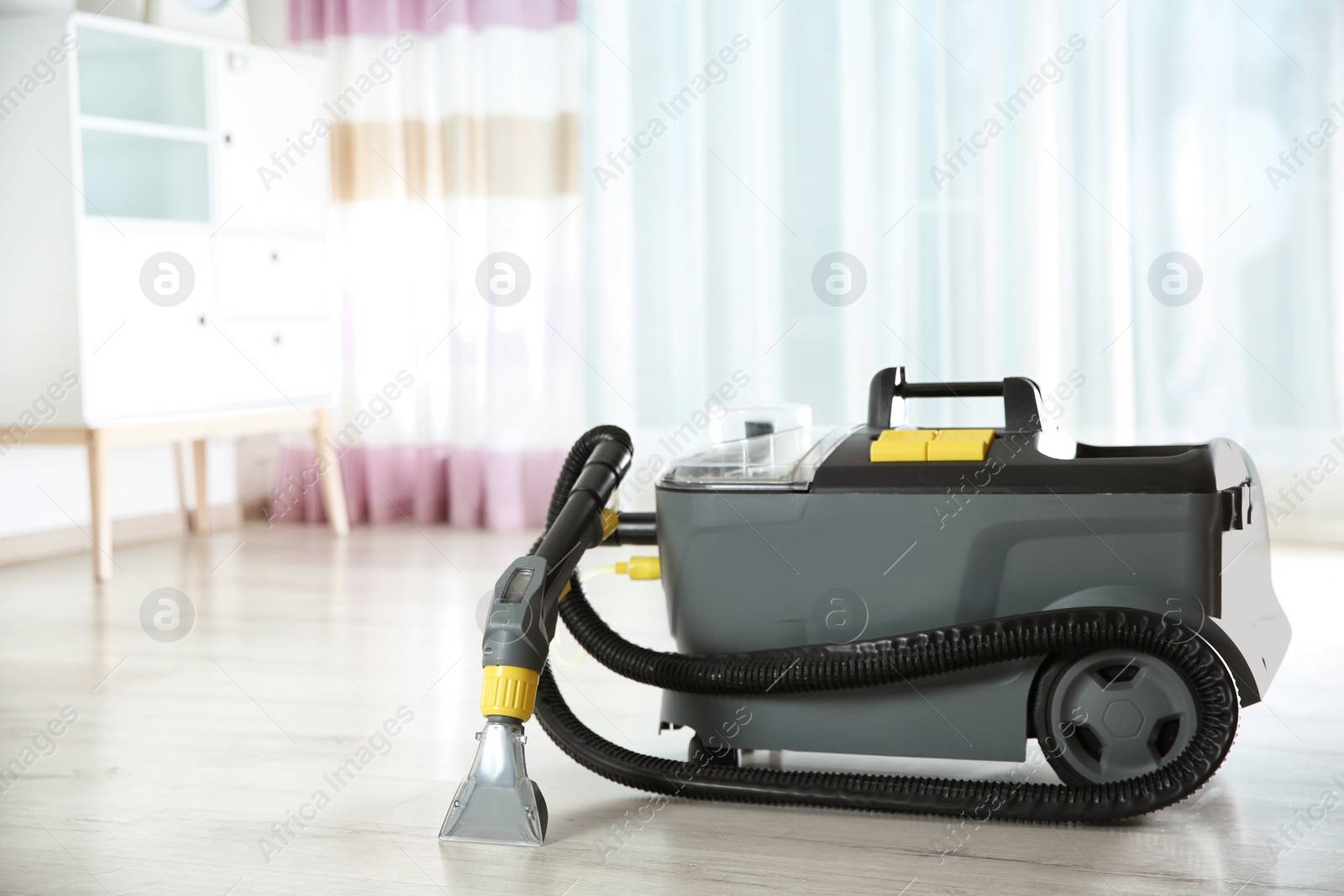 Photo of Wet and dry vacuum cleaner on floor indoors. Space for text