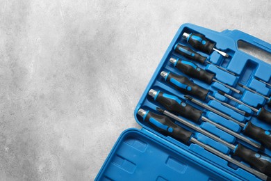 Photo of Set of screwdrivers in open toolbox on light grey textured table, top view. Space for text