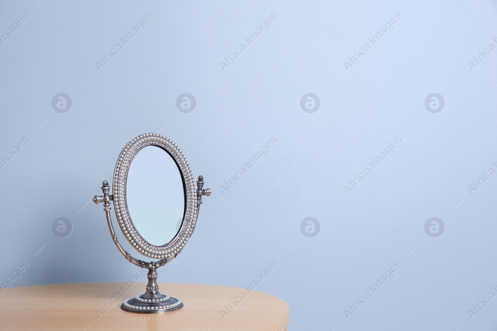 Photo of Stylish mirror on table near light wall