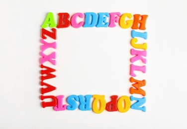 Photo of Frame of colorful magnetic letters on white background, flat lay with space for text. Alphabetic order