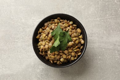 Delicious lentils with parsley in bowl on light grey table, top view