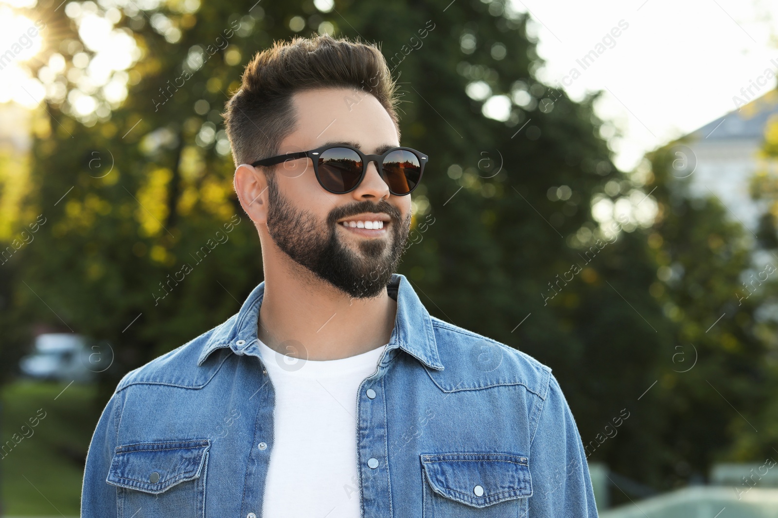 Photo of Handsome smiling man in sunglasses outdoors, space for text