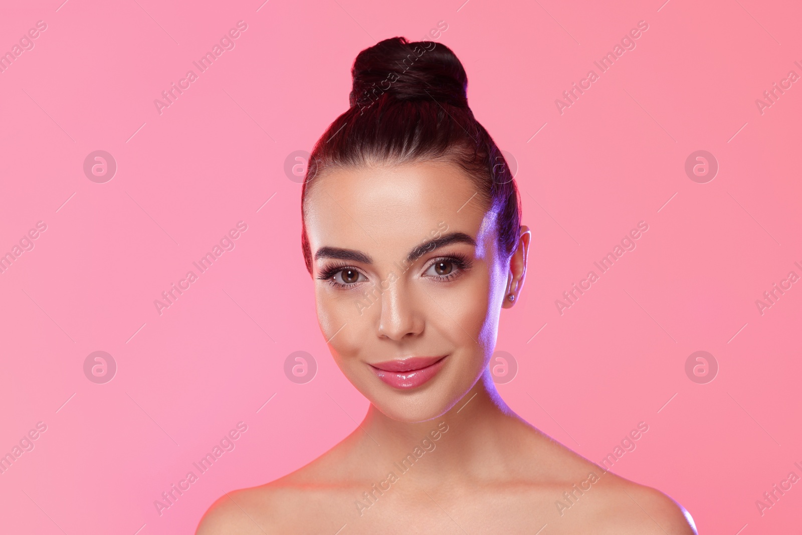 Photo of Portrait of young woman with beautiful makeup on light pink background