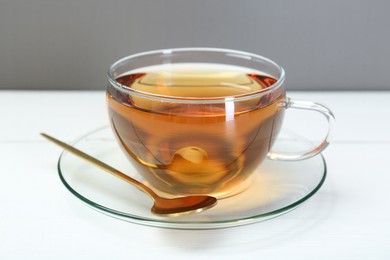 Photo of Glass cup of tea and spoon on white table