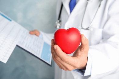 Photo of Doctor holding red heart, closeup view with space for text. Cardiology concept