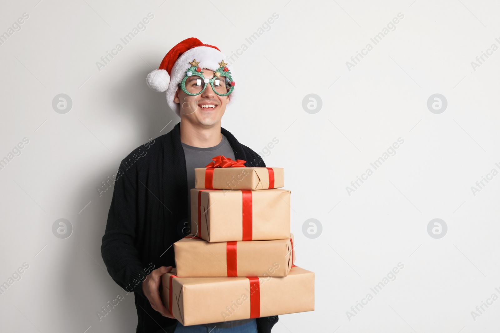 Photo of Young man with Christmas gifts on white background