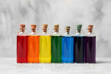 Glass bottles with different food coloring on white table