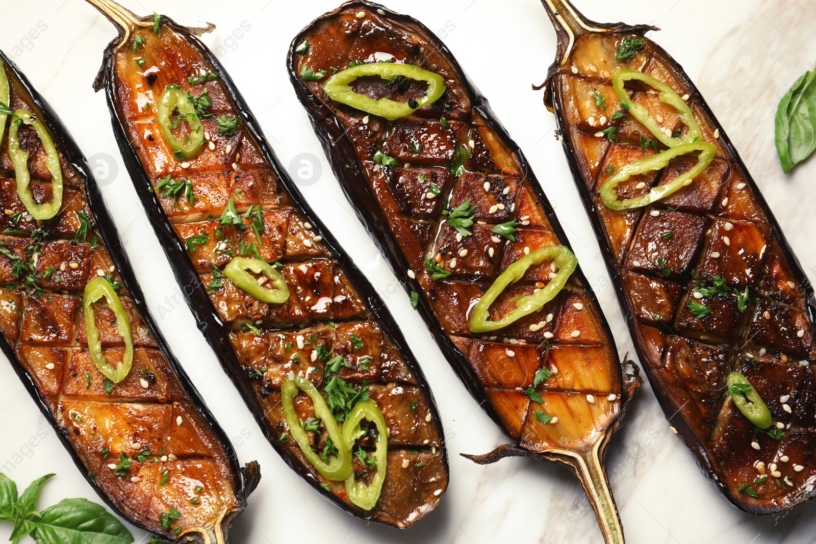 Photo of Fried eggplant slices with chili peppers on light background, closeup