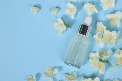 Photo of Essential oil in bottle and beautiful jasmine flowers on light blue background, flat lay. Space for text