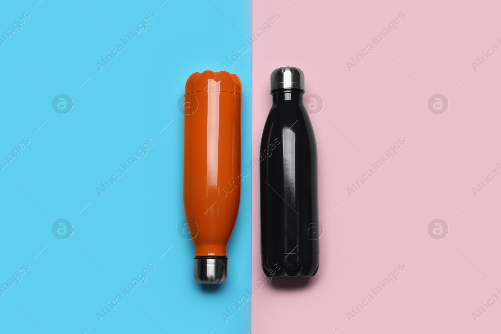 Photo of Modern thermo bottles on color background, flat lay