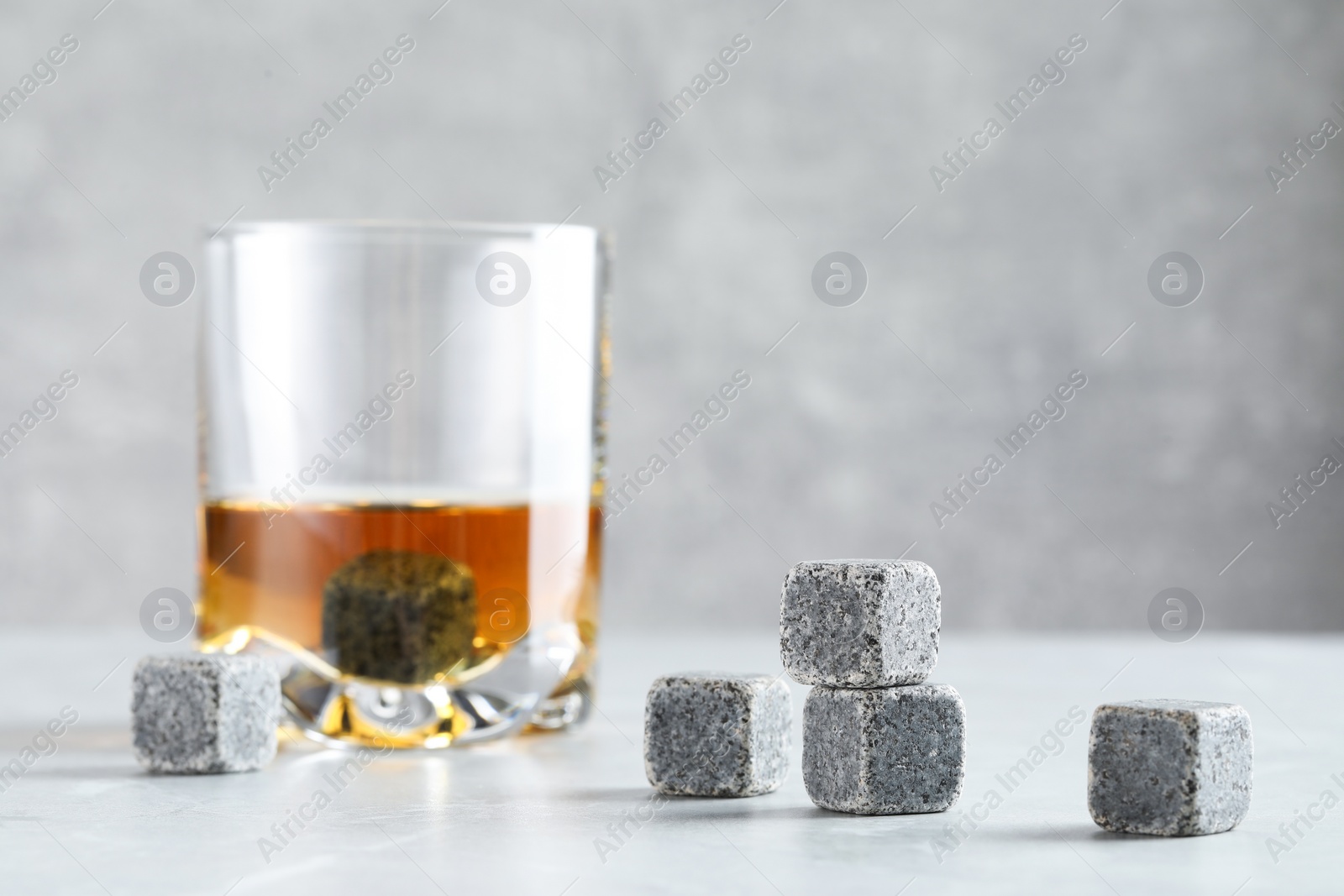 Photo of Whiskey stones and drink in glass on light table, closeup