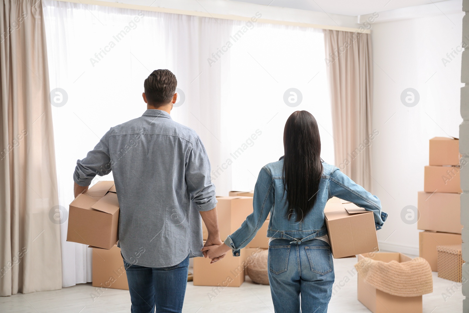 Photo of Couple in room with cardboard boxes on moving day