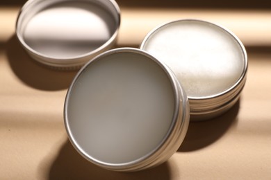 Photo of Lip balms on beige background, closeup view