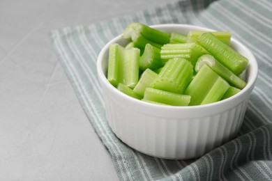 Photo of Bowl with fresh green cut celery on light grey table, closeup. Space for text