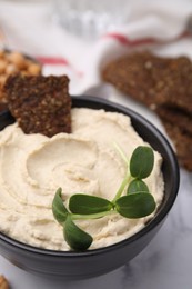 Delicious hummus with crispbread served on white marble table, closeup