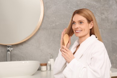 Photo of Beautiful woman brushing her hair in bathroom