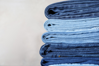 Photo of Stack of different jeans on beige background. Space for text