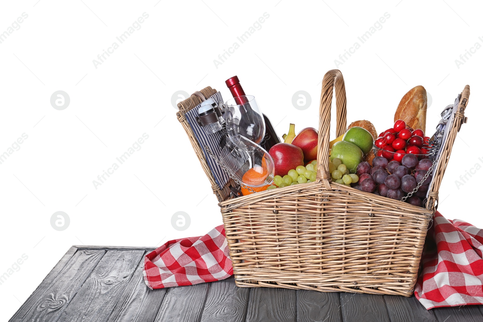 Photo of Wicker picnic basket with wine and different products on wooden table against white background, space for text