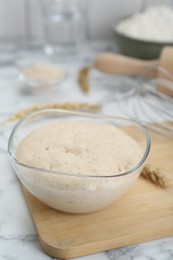 Photo of Leaven and ear of wheat on white marble table