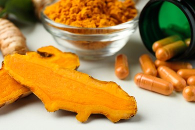 Turmeric roots, pills and powder on white table, closeup