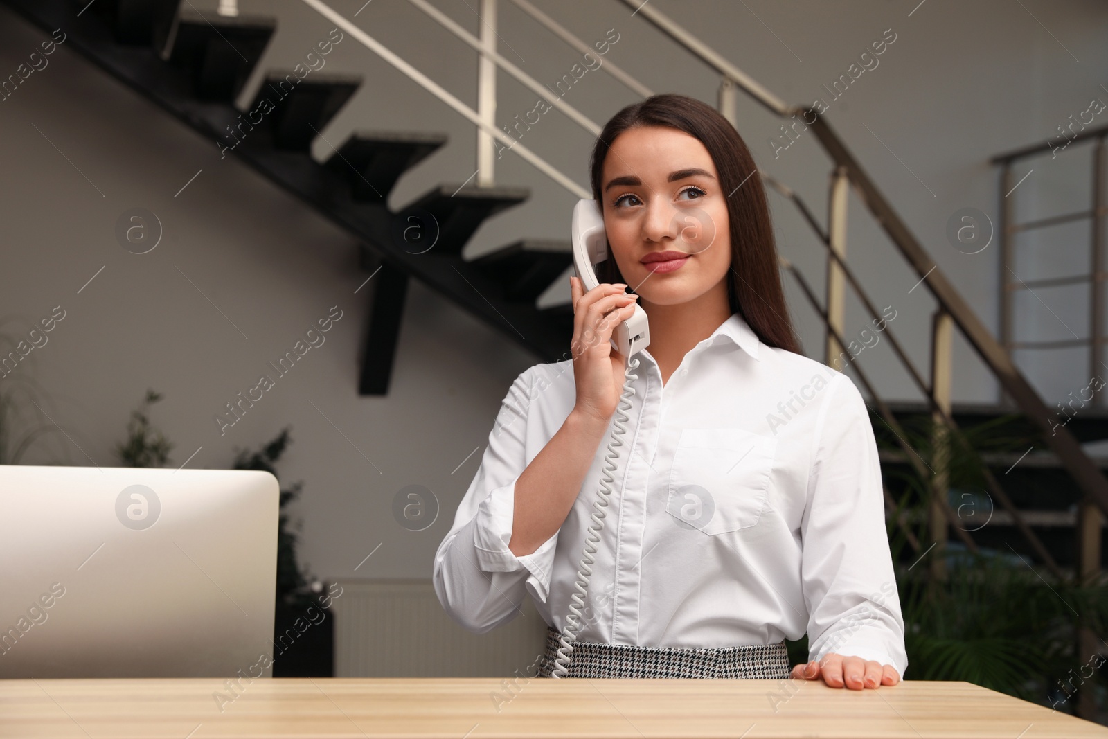 Photo of Female receptionist talking on phone at workplace