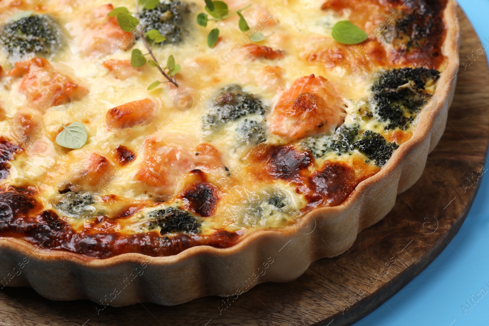 Photo of Delicious homemade quiche with salmon and broccoli on wooden board, closeup