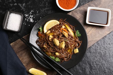 Photo of Stir-fry. Tasty noodles with vegetables and meat served on dark textured table, flat lay