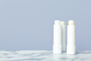 Photo of Hygienic lipsticks on table against grey background