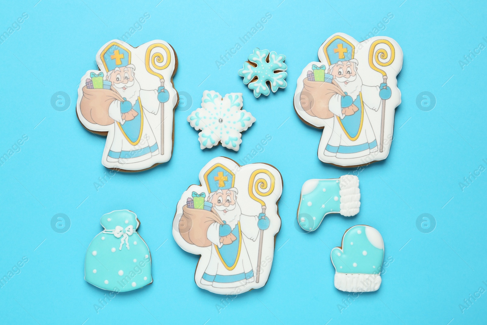 Photo of Tasty gingerbread cookies on light blue background, flat lay. St. Nicholas Day celebration