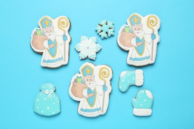 Tasty gingerbread cookies on light blue background, flat lay. St. Nicholas Day celebration