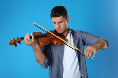 Man playing violin on light blue background