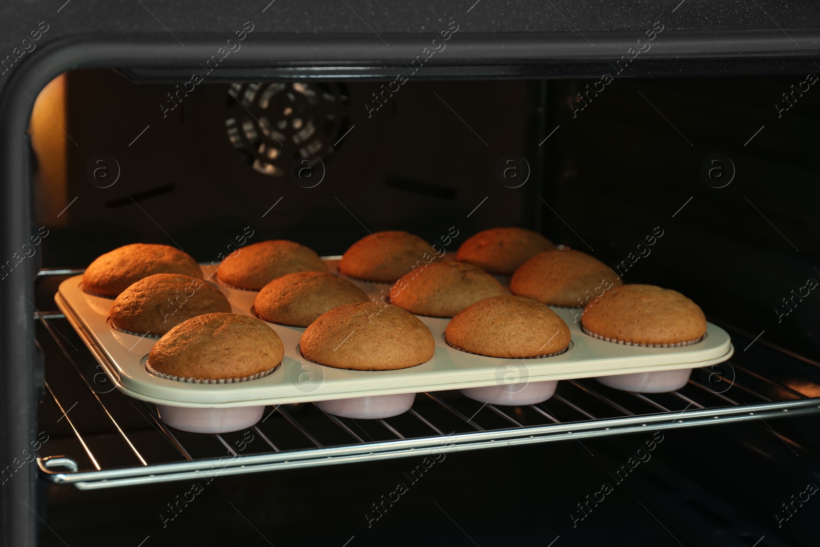 Photo of Baking pan with cupcakes in modern oven