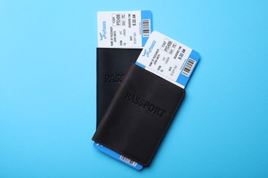 Photo of Passports with avia tickets on light blue background, flat lay. Travel agency concept