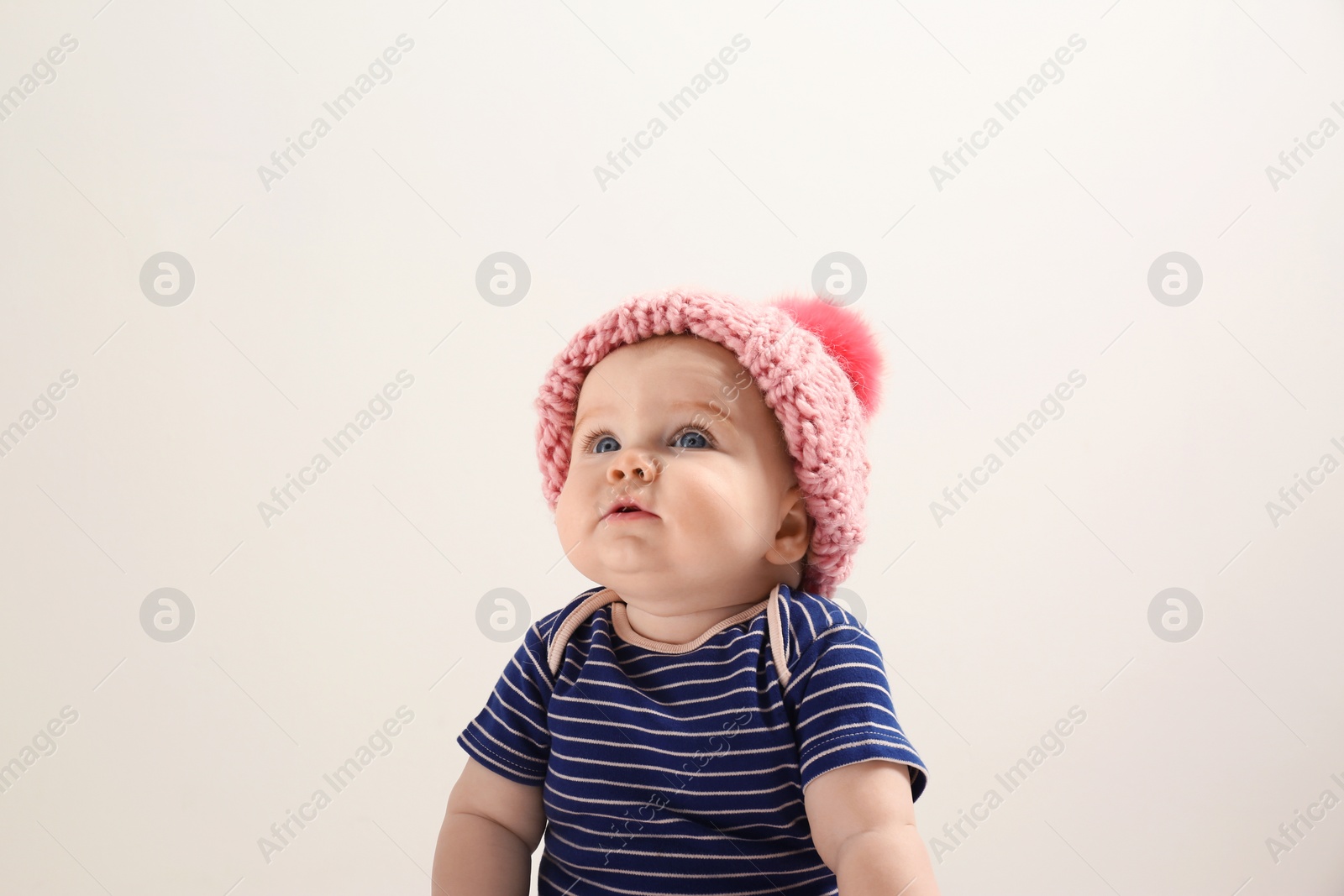Photo of Little child in knitted hat on light background. Baby accessories