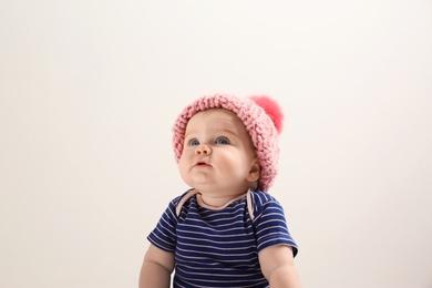 Little child in knitted hat on light background. Baby accessories