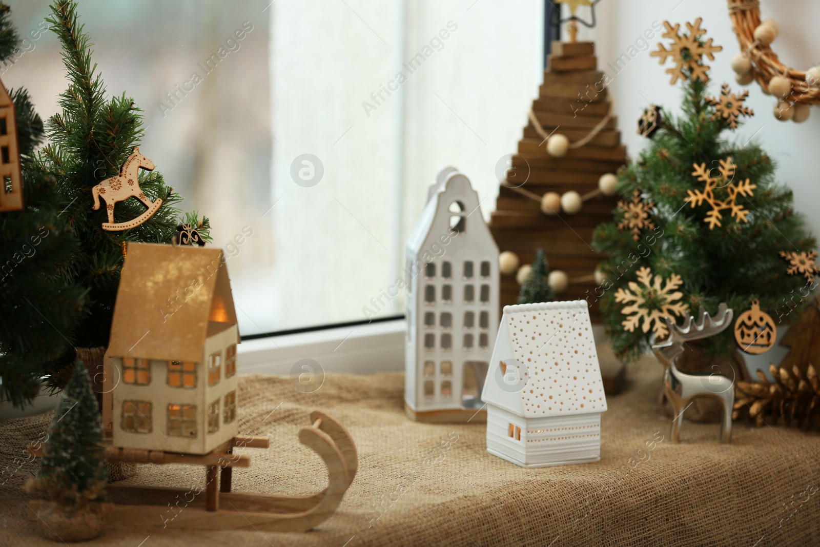 Photo of Beautiful window sill decorated for Christmas with small houses and fir trees indoors