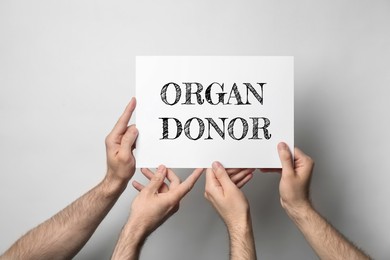 Image of Men holding card with text ORGAN DONOR on light background, closeup 