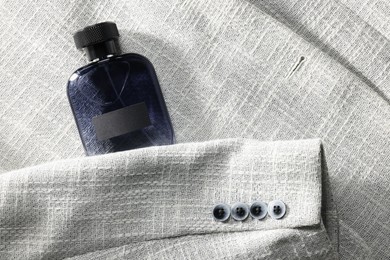 Luxury men's perfume in bottle on grey jacket, top view. Space for text