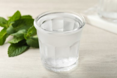 Glass of soda water and mint on white wooden table