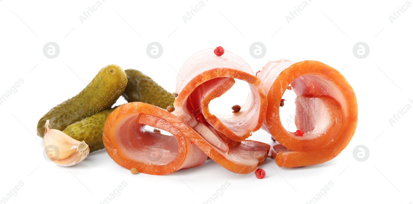 Photo of Slices of delicious smoked bacon with peppercorns, garlic and pickled cucumbers on white background