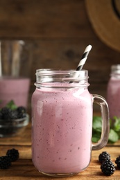 Photo of Tasty fresh milk shake with blackberries on wooden table