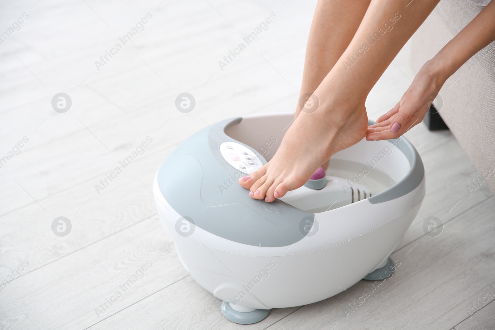 Photo of Woman with beautiful legs using foot bath at home, closeup with space for text. Spa treatment